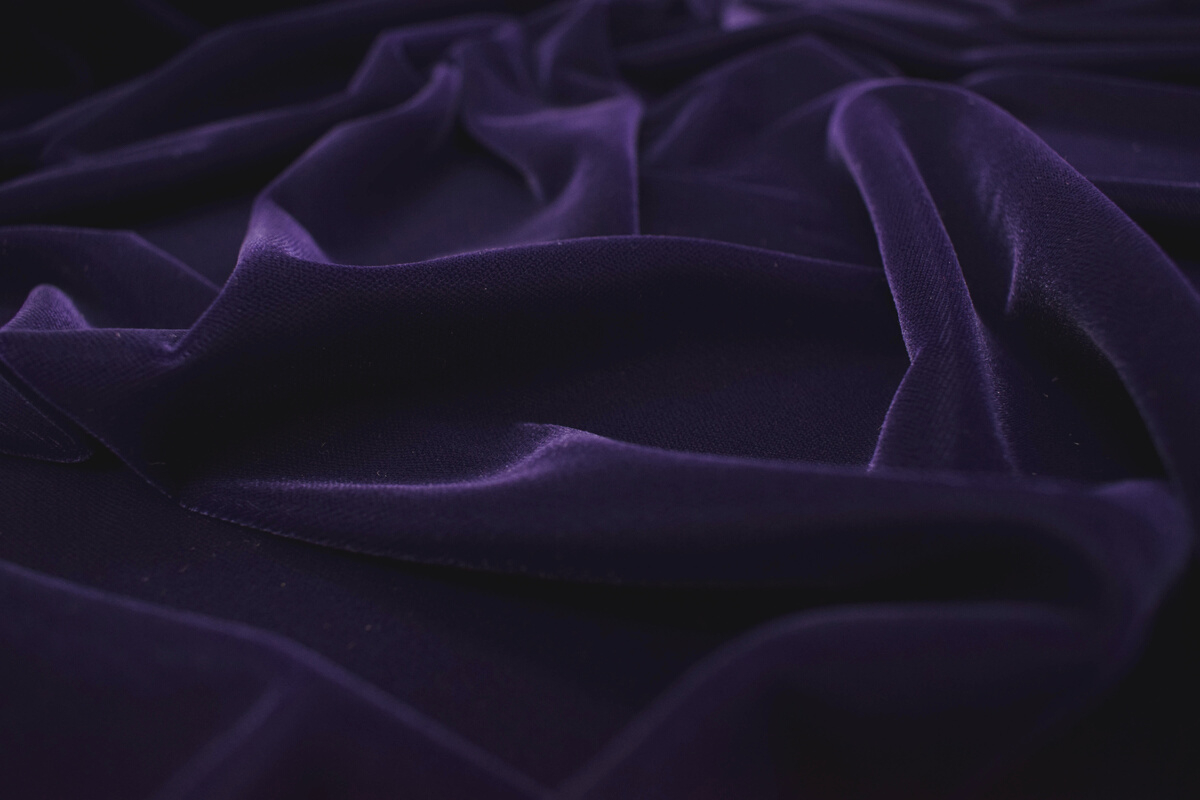 Dark purple velvet fabric texture background.